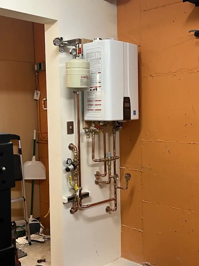 Plumbing technician inspecting water heater connections in College